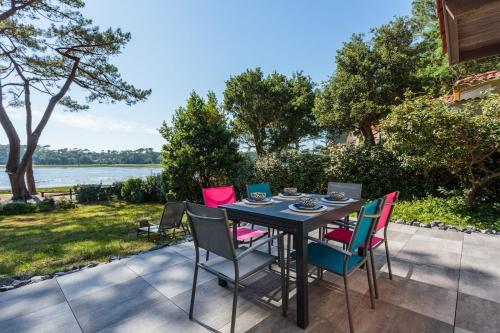 - une table et des chaises sur une terrasse avec vue sur l'eau dans l'établissement La Maison du Lac - Welkeys, à Soorts-Hossegor