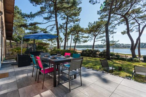 d'une terrasse avec une table et des chaises offrant une vue sur l'eau. dans l'établissement La Maison du Lac - Welkeys, à Soorts-Hossegor