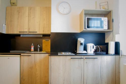 une cuisine avec des armoires en bois et une horloge au mur dans l'établissement Le Colibri - Parking Wifi, à Besançon