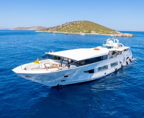 a white boat in the water with an island in the background at Yalikavak Matilda Mega Yacth Hotel in Bodrum City