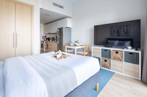 a bedroom with a large white bed and a television at Frank Porter - Azizi Aura in Dubai