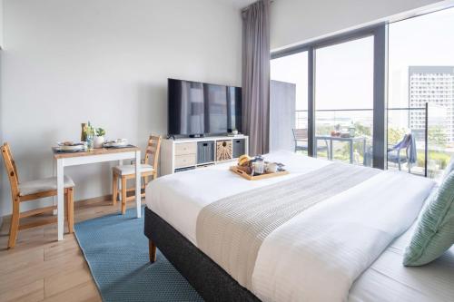 a bedroom with a large bed with a desk and a balcony at Frank Porter - Azizi Aura in Dubai