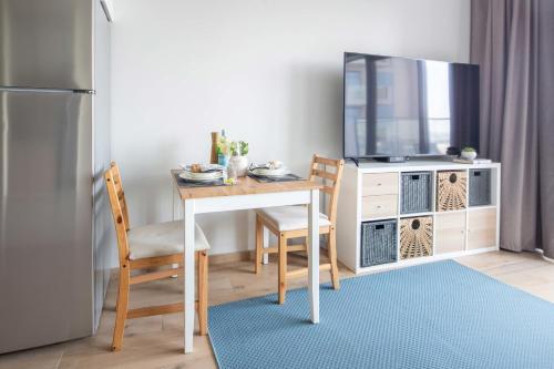 a dining room table with a tv and a table and chairs at Frank Porter - Azizi Aura in Dubai