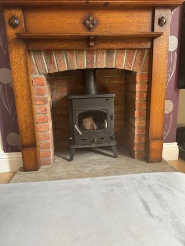 a brick fireplace with a stove in a room at The Perfect Bedroom to Rent in Altofts
