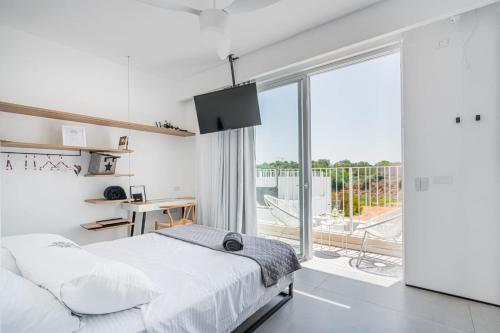 a white bedroom with a bed and a balcony at Danielle boutique suite in Caesarea