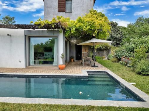 - une piscine avec un parasol en face d'une maison dans l'établissement Spacieuse Villa avec Piscine & Jardin - Hébergement Classé, à Plan-de-Cuques