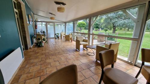 Cette chambre comprend des chaises, des tables et de grandes fenêtres. dans l'établissement Domaine de Bernede, à Pomarez