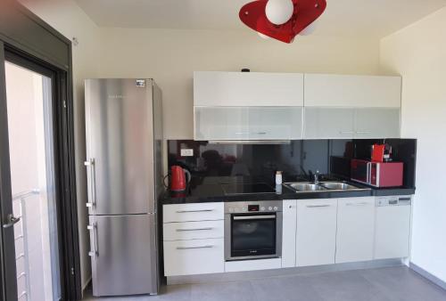 a kitchen with white cabinets and a stainless steel refrigerator at Andromeda Sea View Villa in Epáno Eloúnda