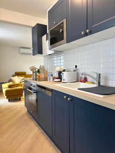 - une cuisine avec des placards bleus, un évier et une cuisinière dans l'établissement Charmant Studio à Étampes, Netflix, à Étampes