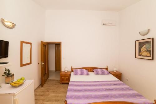 a bedroom with a large bed with purple pillows at Villa Nada - room for 2 in Duće