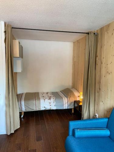 une chambre avec un lit et une chaise bleue dans l'établissement Studio chaleureux rénové, à Allemont