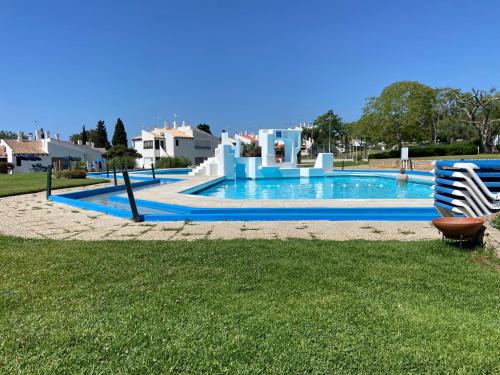 a swimming pool in a yard next to a lawn with a chair at Apartamento Pedras Del Rei - Casa Azul in Tavira