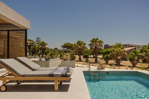 a pool with two lounge chairs next to a swimming pool at Mast Luxury Residences in Gargaliánoi
