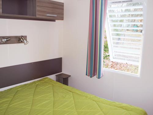 a bedroom with a green bed and a window at Camping maeva Respire de La Croze in Châtel-Guyon