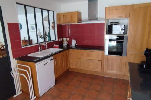 - une cuisine avec des placards en bois et un évier blanc dans l'établissement Villa tout confort avec piscine, à Mauguio