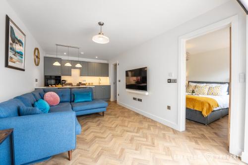 a living room with a blue couch and a bed at Harbour Haven by Grandeur Property in Poole