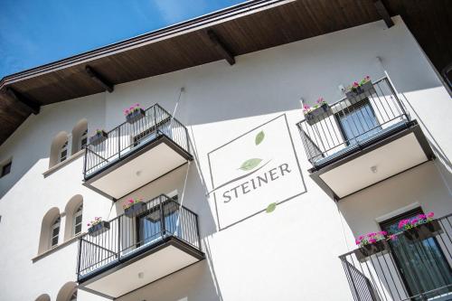 a white building with balconies and a sign on it at Hotel CampingPark Steiner in Laives
