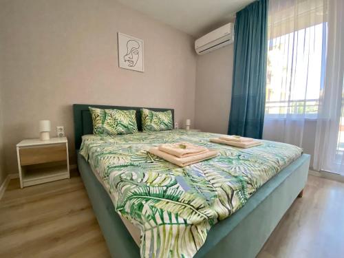 a bedroom with a bed with a green comforter at AVRORA SUITE in Varna City