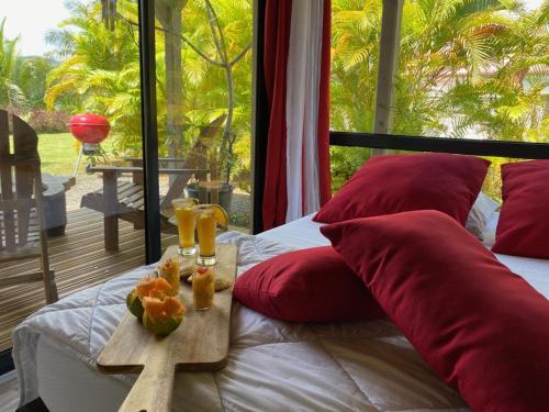 a bed with red pillows and a tray of fruit on it at Hauolibed - Havre de Passion avec piscine in Sainte-Rose