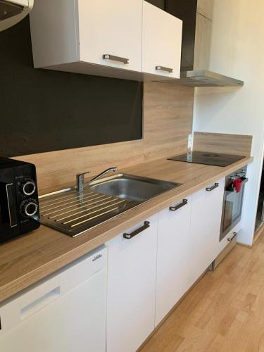 une cuisine avec des armoires blanches et un évier dans l'établissement Duplex du Lion - 8 Voyageurs - Appartement 4 chambres supérieures, à Belfort