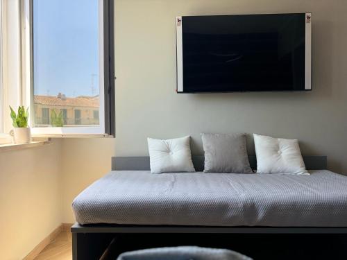 a bedroom with a bed with a flat screen tv on the wall at SKY LUXURY Rooms Nettuno in Nettuno