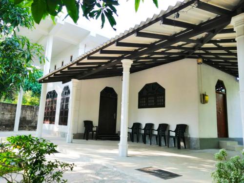 a patio with black chairs under a wooden pergola at Green Hill Villa in Unawatuna