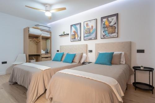 two beds in a room with white walls and blue pillows at Apartamento Luxor en zona Hospital - Universidad in Albacete