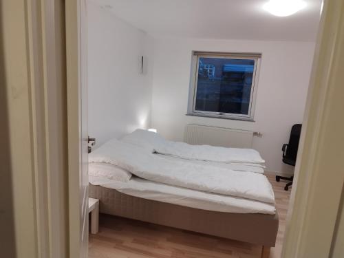 a bedroom with a bed with white sheets and a window at Fjeldgaard in Odense