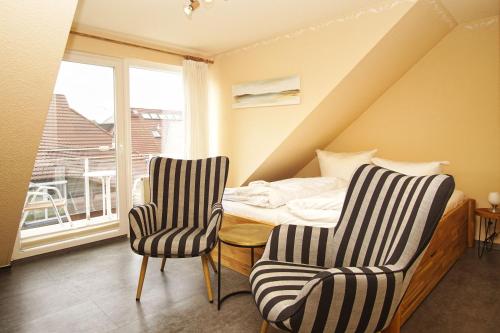 a bedroom with two chairs and a bed and a window at Apartmentanlage Eldena Ferienwohnung 10 in Lobbe