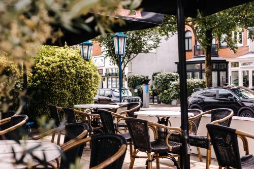 an outdoor cafe with tables and chairs and an umbrella at Hotel Keur - Apartments in Zandvoort