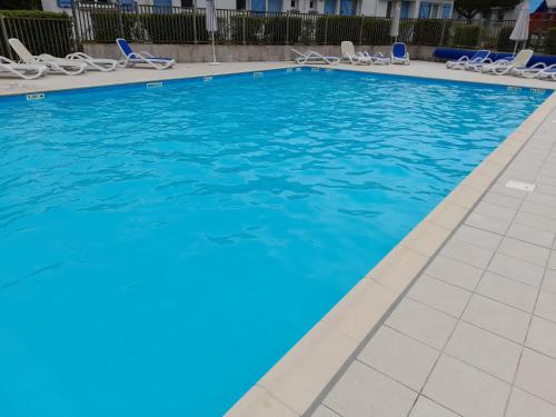 - une piscine avec des chaises et de l'eau bleue dans l'établissement Maison 4-6 personnes, à Saint-Brévin-les-Pins