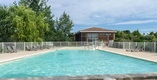 une grande piscine avec des chaises et un bâtiment dans l'établissement Maison 3 pièces 6 personnes, à Saint-Saturnin-lès-Avignon