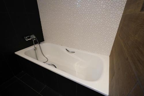 a white bath tub in a black tile bathroom at Hotel Mas Prades in Deltebre