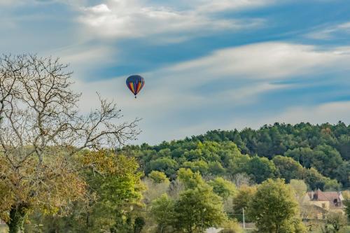 a hot air balloon is flying in the sky at Maison en pierre piscine clim in Varennes