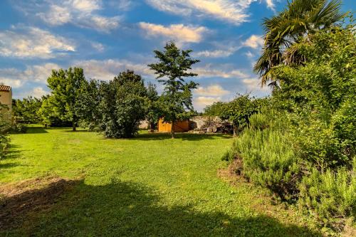 a field of grass with trees and a palm tree at Maison en pierre piscine clim in Varennes