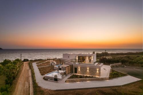 a house on the beach with the ocean in the background at Mast Luxury Residences in Gargaliánoi