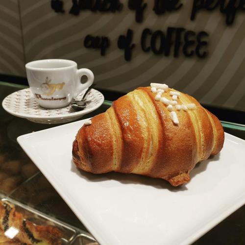 un dolce su un piatto bianco accanto a una tazza di caffè di GLIKA APPARTAMENTO NAPOLETANO a Napoli
