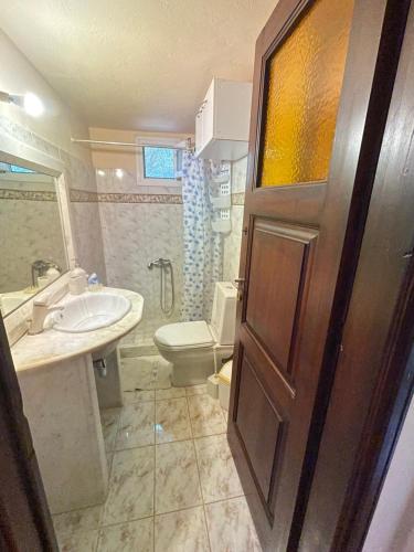 bagno con servizi igienici, lavandino e porta di Μονοκατοικία Στο Λουτρακι a Loutraki