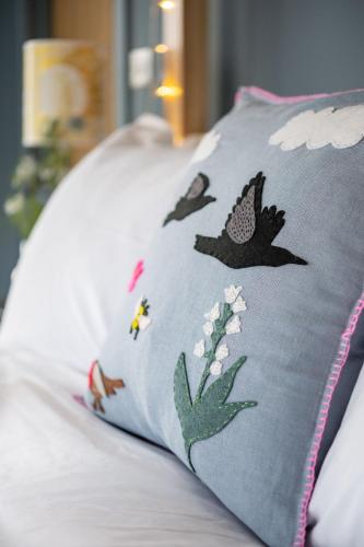 a pillow with birds and flowers on a bed at The Art Loft in Kingsbridge