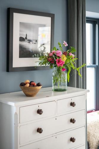 a white dresser with a vase of flowers on it at The Art Loft in Kingsbridge