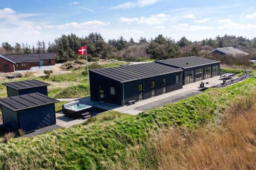 a black building with a flag on top of a field at Luxurious Holiday Home With Sauna And 5-Person Outdoor Spa -1018 in Ringkøbing