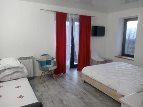 a bedroom with a bed and red curtains and a chair at Casa Prieteniei - rezervare integrală in Bistriţa