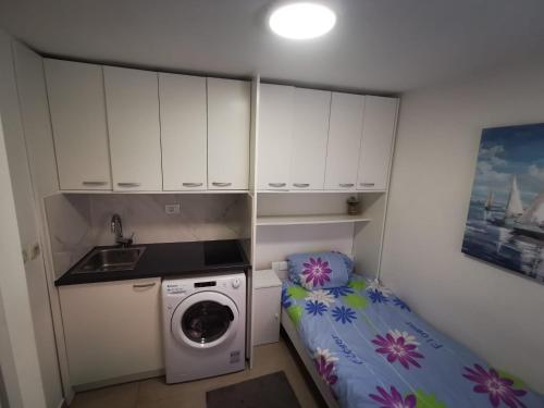 a small kitchen with a washing machine and a bed at Adriatic Stone House Hunič in Umag