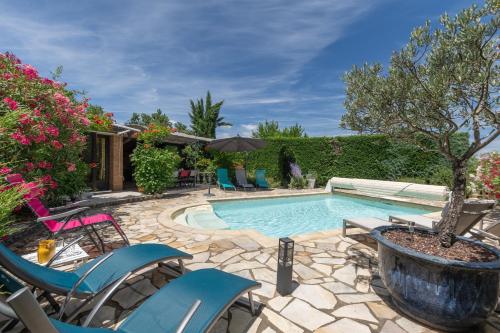 une piscine avec des chaises et un arbre dans une cour dans l'établissement Mas Le Bragalou, à Courry