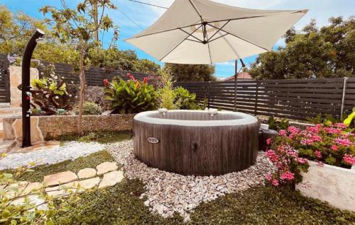 un giardino con un ombrellone e una vasca circolare di legno di Beautiful Home In Sibenik With Wifi a Šibenik