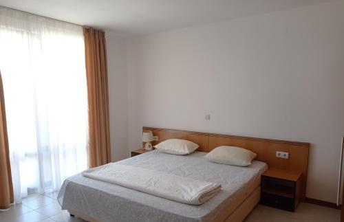 a bedroom with a bed and a large window at Апартамент Къмпинг Градина in Chernomorets
