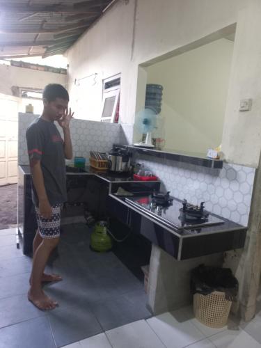 a man standing in a kitchen next to a sink at Esvania Homestay2 in Seturan