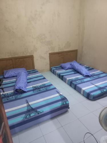 three beds are lined up in a room at Esvania Homestay2 in Seturan