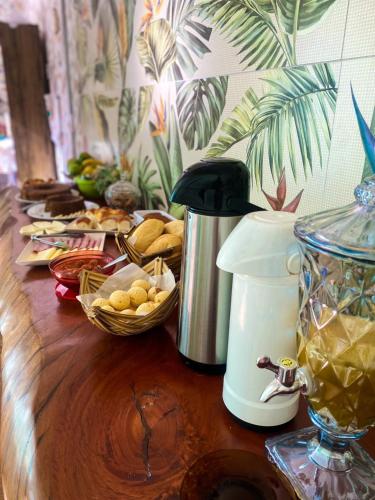 a table with a coffee maker and a basket of food at Pousada Cardeal Mota in Serra do Cipo