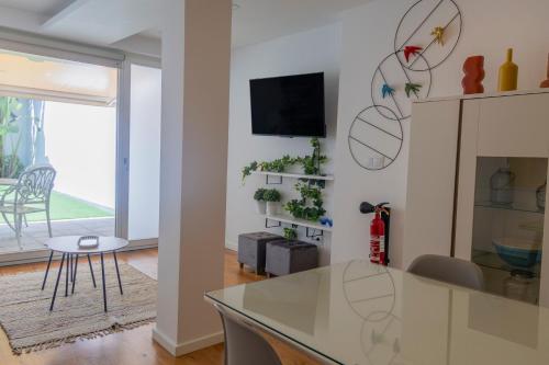 a living room with a table and a tv on a wall at Casa das Falcoeiras - AL com pátio e jardim privados in Aveiro